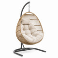 Sillón colgante de ratán con cojín beige y estructura de acero